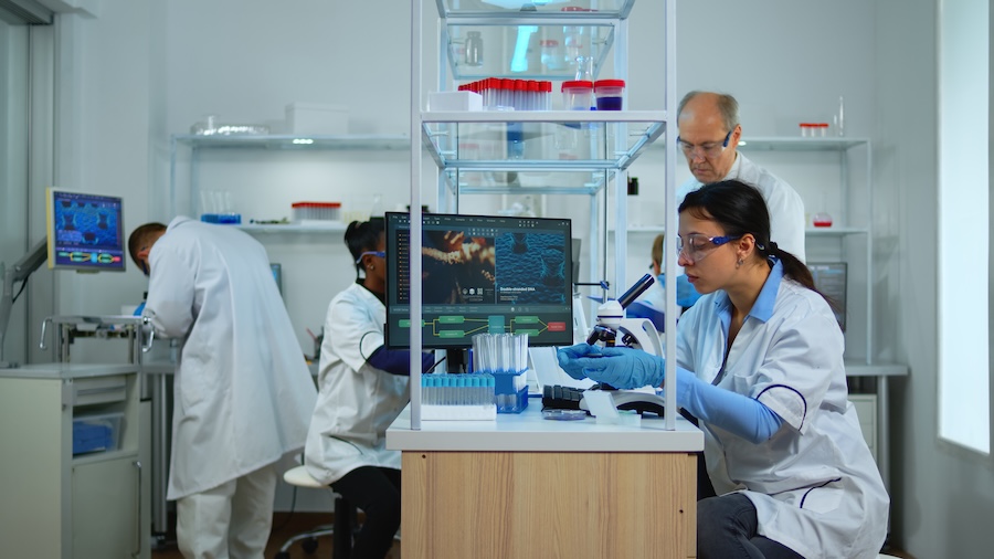 Professional scientists team preparing vaccine against new virus in modern equipped laboratory. Multiethnic team examining treatment evolution using high tech, chemistry tools for scientific research